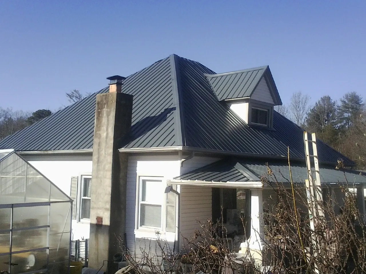 Dark blue standing seam metal roof on a white farmhouse with dormer — Slate & Tile Roof Repair by Roofing Brothers in Catskill