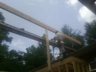 Carpenter setting a ridge beam over a new addition frame — Ice Dam Removal by Roofing Brothers in Catskill