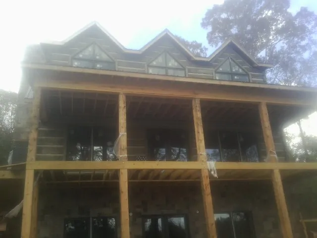 Dormers and porch framing on a large log home under construction — Roof Coating work by our crew in Catskill