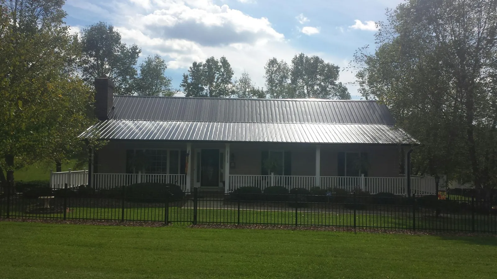 Gray metal roof on a brick ranch with a full width front porch — Gutter Guard Installation work by our crew in Catskill