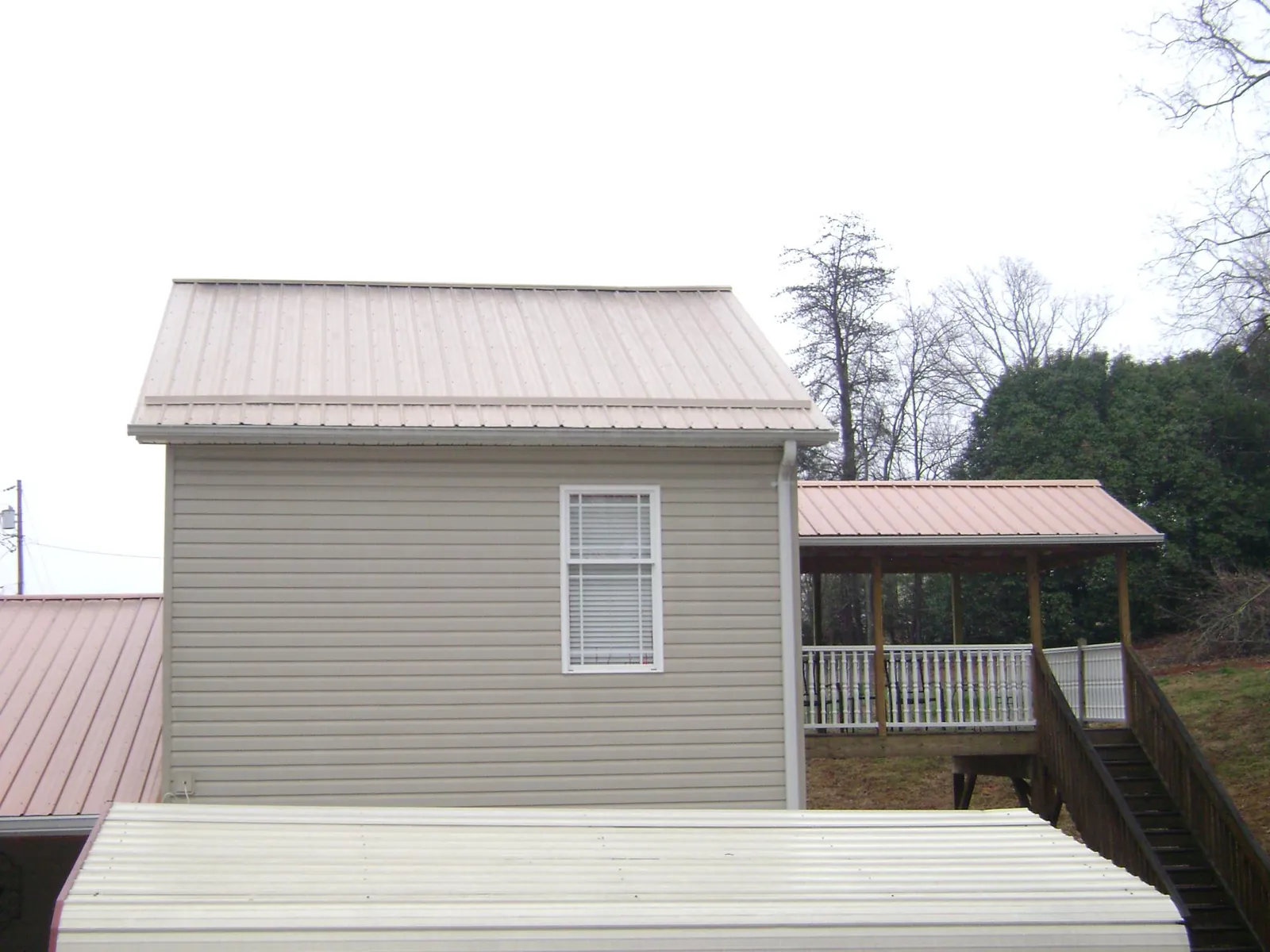 Tan metal roofs on a two story addition and attached porch, from a Roof Replacement job in Catskill