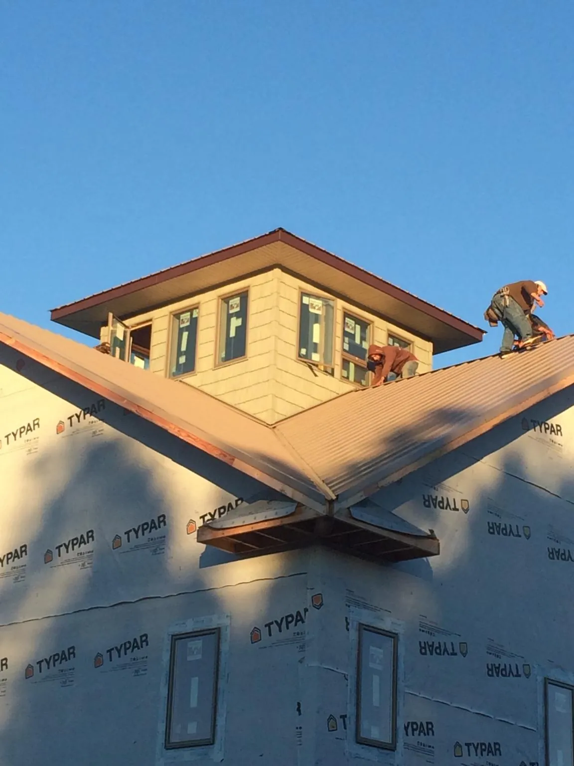 Roofers working around a rooftop cupola on a new metal roof at sunset — Roof Waterproofing in Catskill by Roofing Brothers